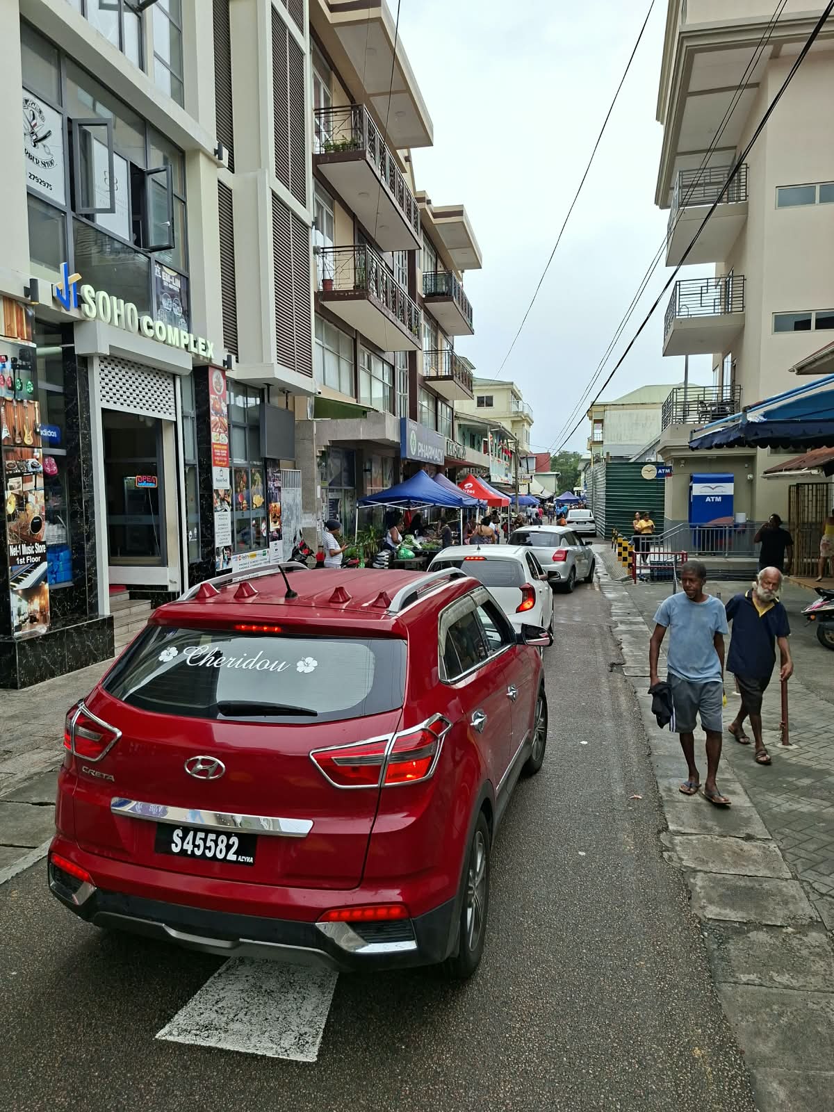 Busy Victoria market street with shops, stalls and local traffic